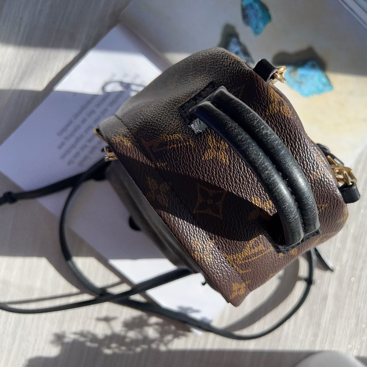 Louis Vuitton monogram handbag on a textured surface with a blurred background