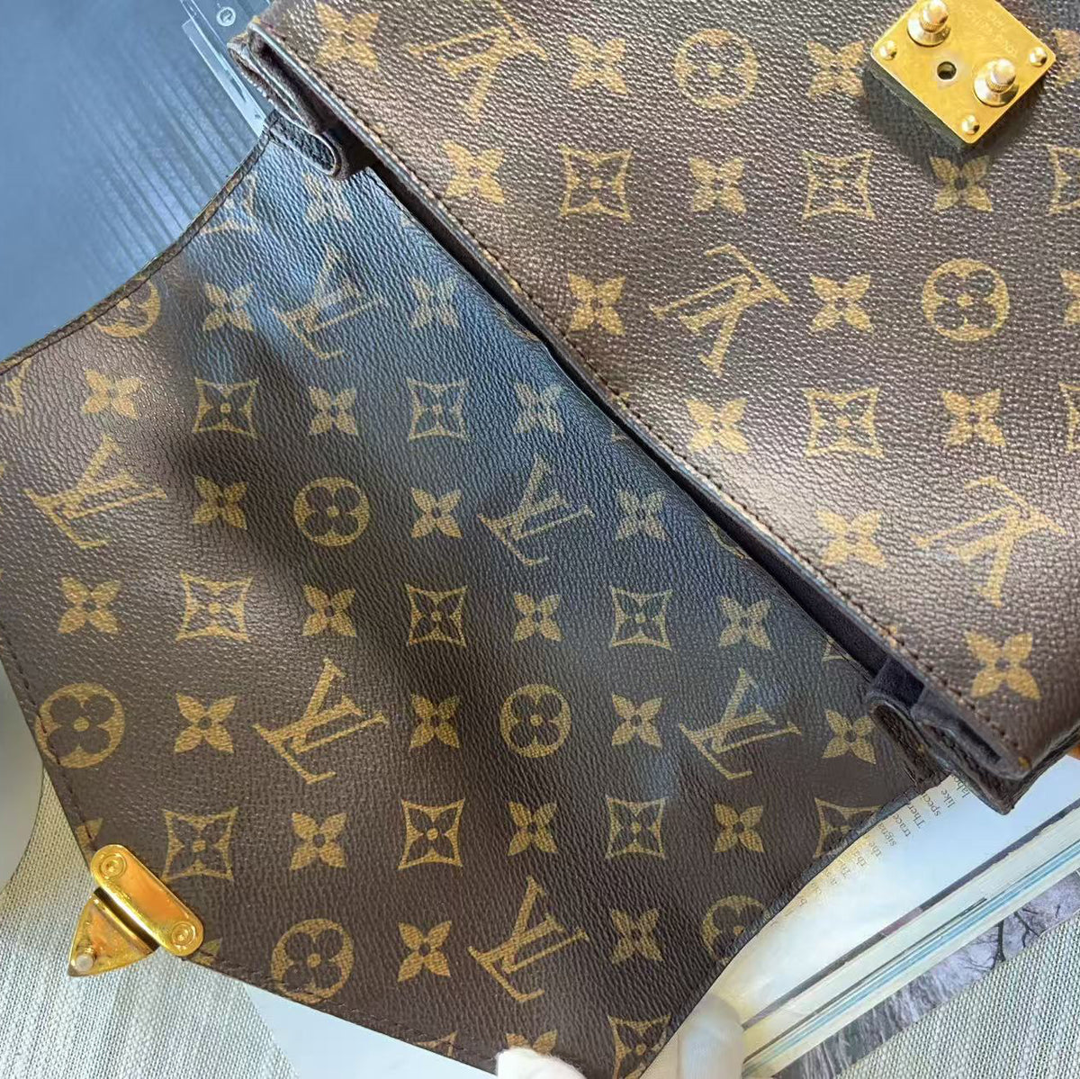 A Louis Vuitton monogram canvas handbag shown in a close-up angled view, featuring the classic brown and beige LV pattern with gold-tone hardware.