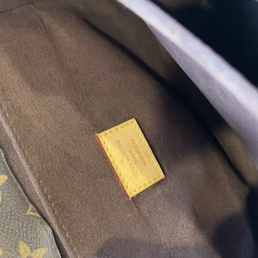 Close-up of a Louis Vuitton monogram bag interior showing a brown suede lining and a small yellow leather brand patch with embossed text.