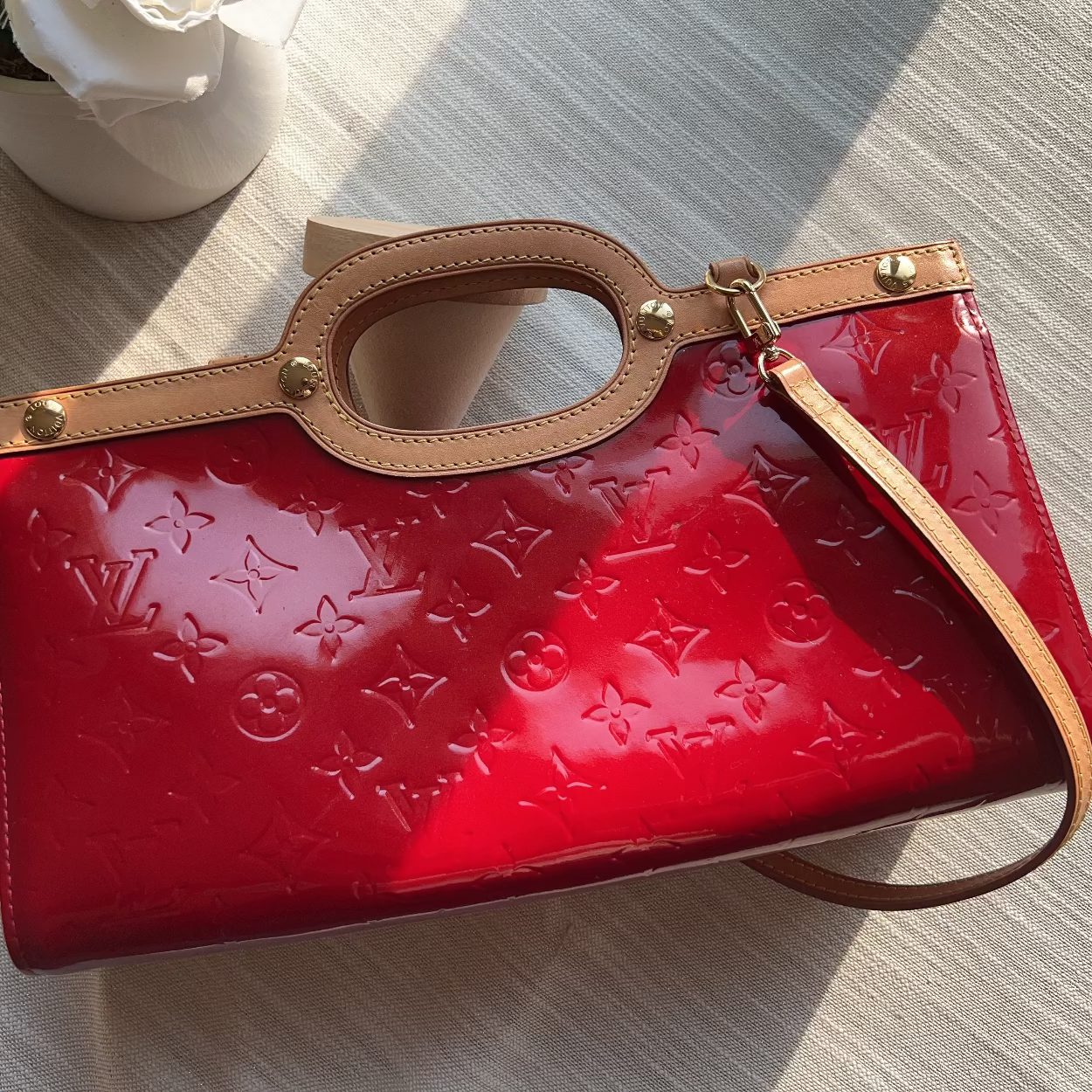 Red embossed handbag with brown handle on a light gray surface