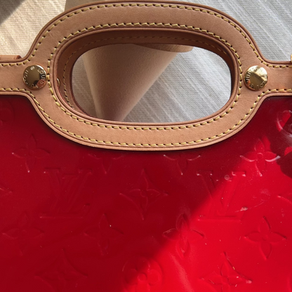Close-up of a brown leather dog muzzle on a red surface with a white cup in the background.