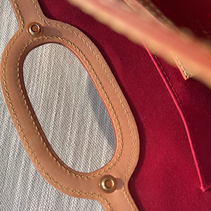 Close-up of a brown leather handle with stitching on a red fabric background