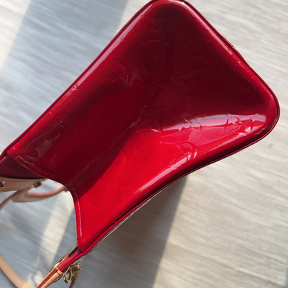 Red handbag on a light wooden surface