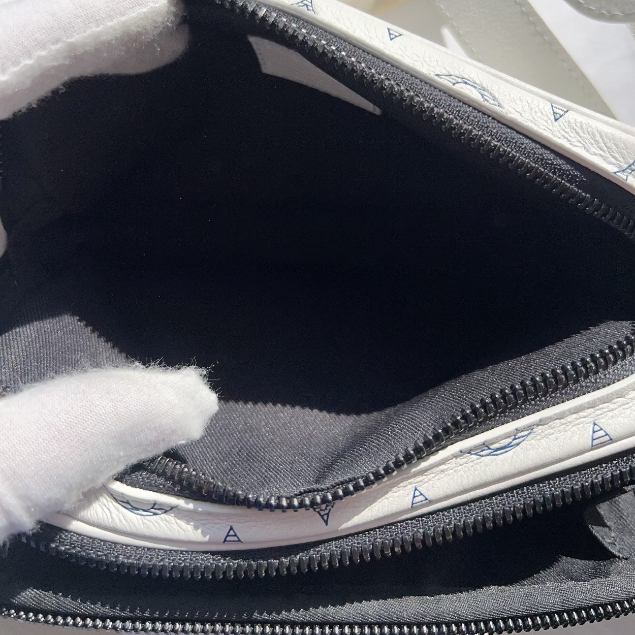 Close-up of a zipped bag with a white interior and gray exterior, showing signs of wear.