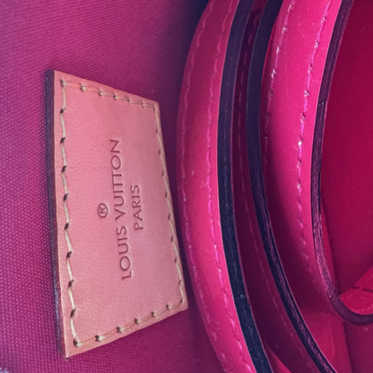 Close-up of a Louis Vuitton Paris interior showing a pink leather brand patch with debossed text on a magenta fabric background.