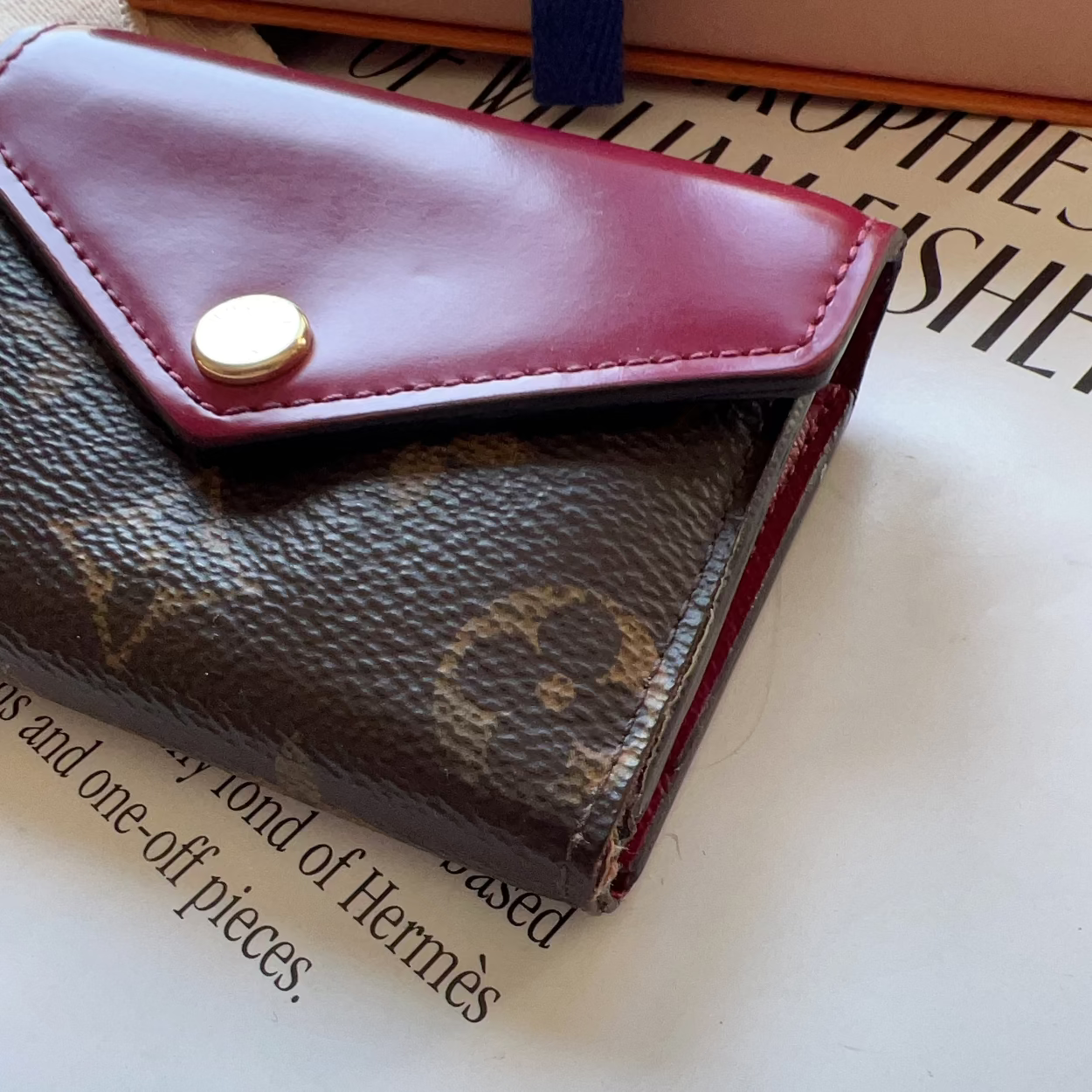 Close-up of a maroon wallet with a gold button on a magazine page.