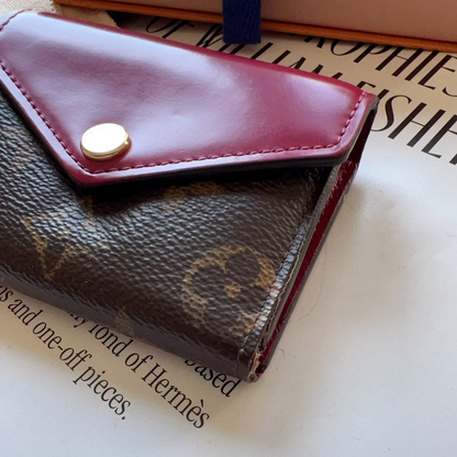 Close-up of a maroon wallet with a gold button on a magazine page.