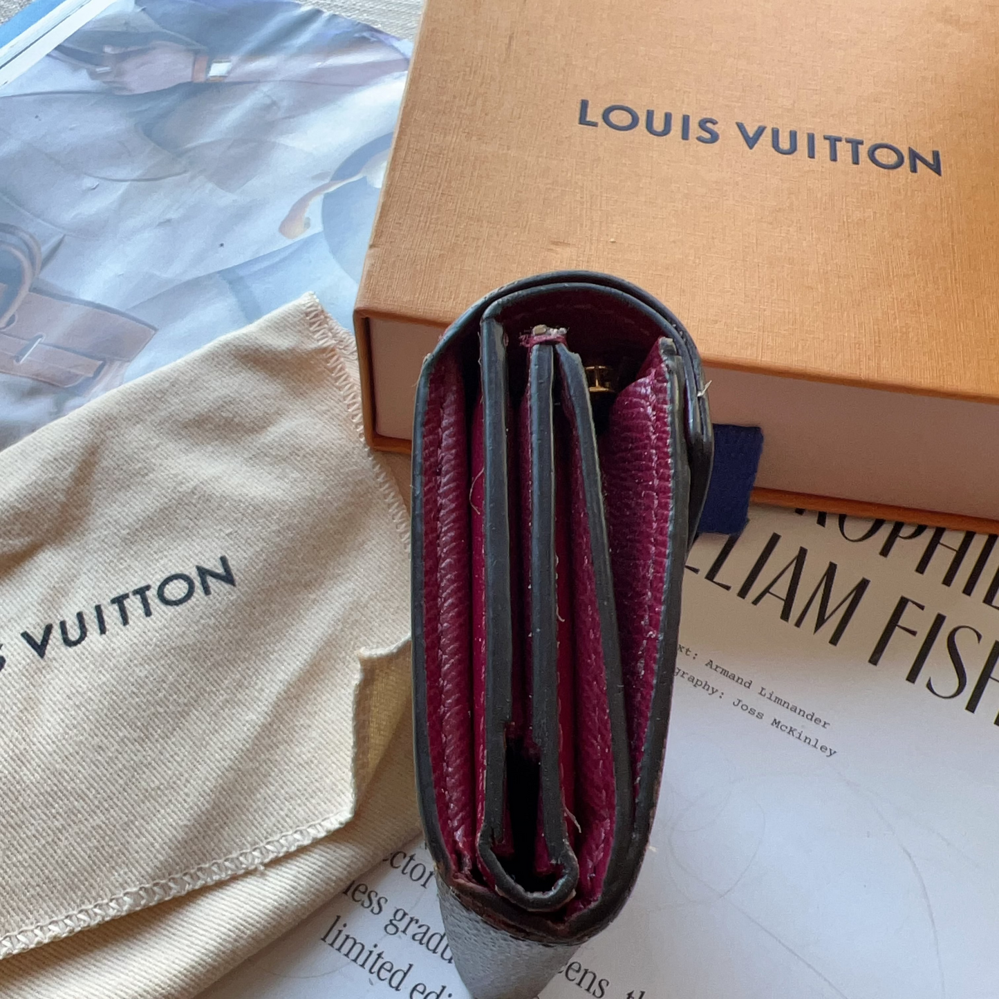 Louis Vuitton wallet and pouch on a magazine with visible branding