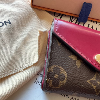 Louis Vuitton wallet on a surface with a beige cloth and book in the background