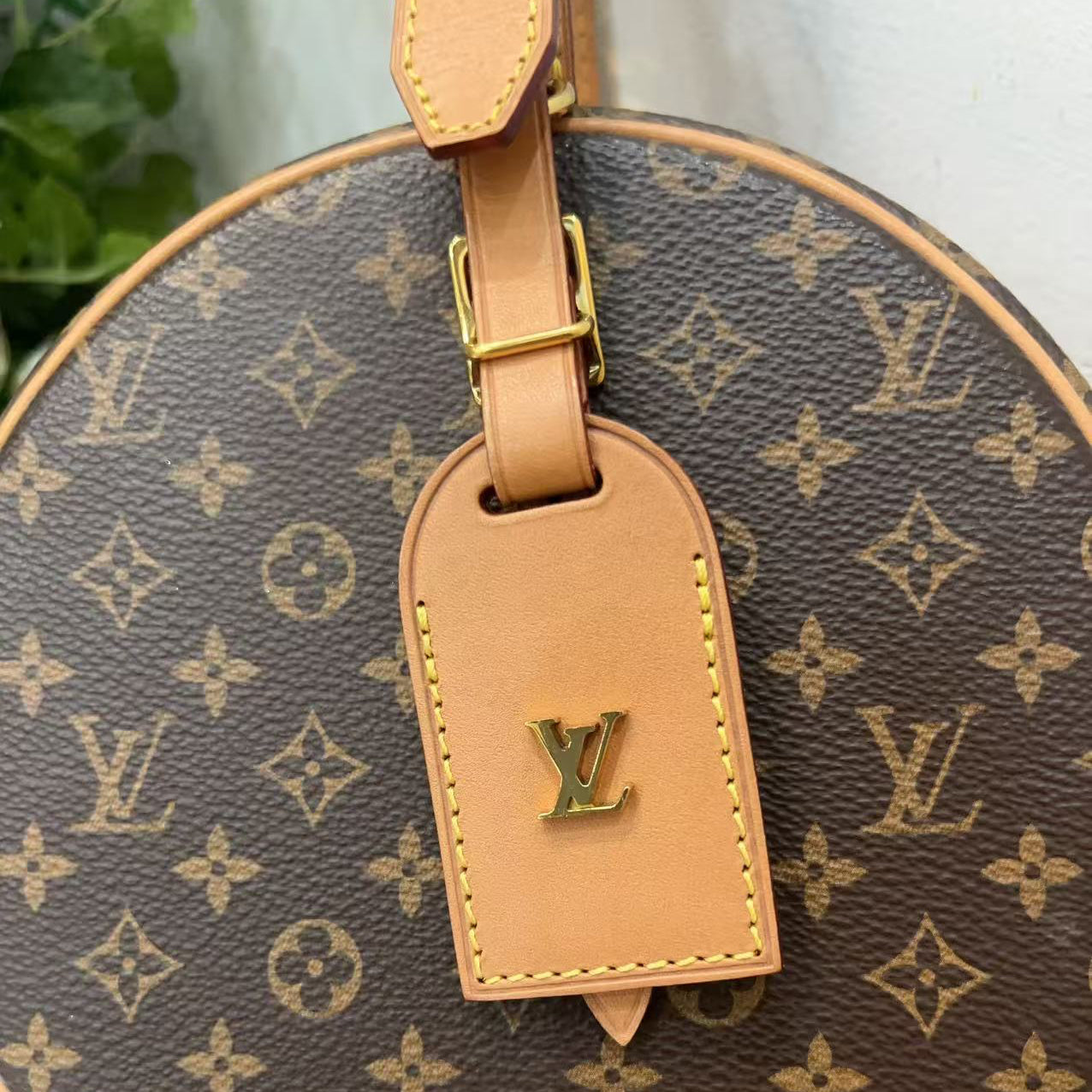 Louis Vuitton monogram bag with a visible logo tag on a neutral background