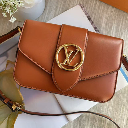 Brown handbag with gold emblem on a surface with flowers and books
