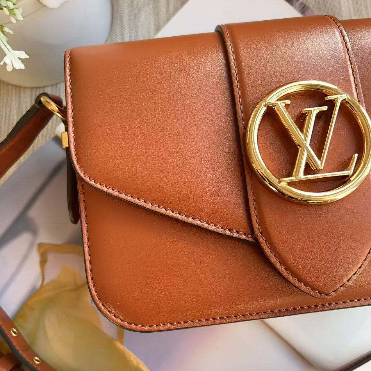 Brown leather handbag with gold logo on a blurred background