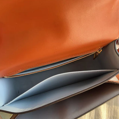 Close-up of a brown leather bag with a blue interior on a wooden surface.
