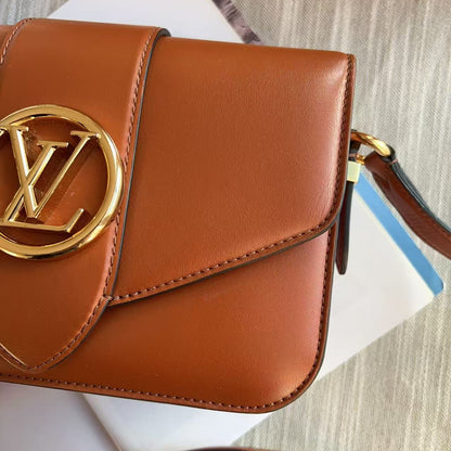 Brown leather handbag with gold logo on a textured surface