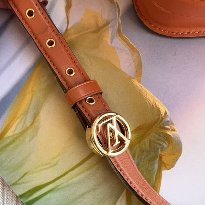 Brown leather belt with gold buckle on a yellow fabric background