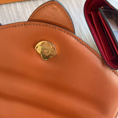 Brown leather bag with gold emblem on a textured surface