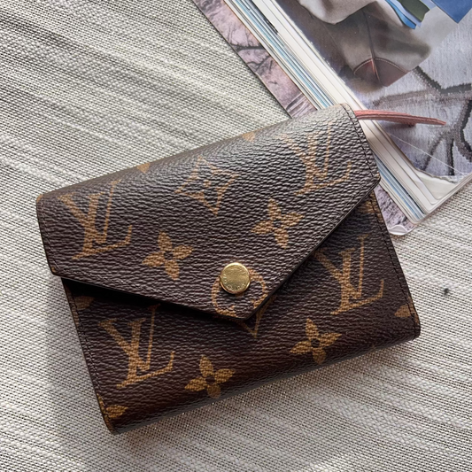 Louis Vuitton wallet on a textured surface with a magazine in the background