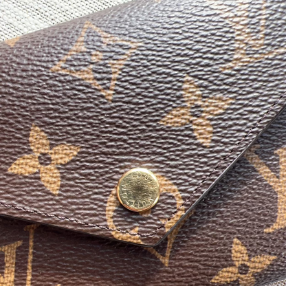 Close-up of a brown leather wallet with gold monogram pattern