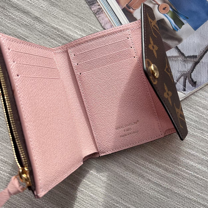 Pink wallet with gold accents on a textured surface