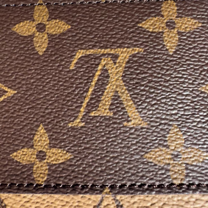 Close-up of a brown leather bag with a prominent logo pattern.