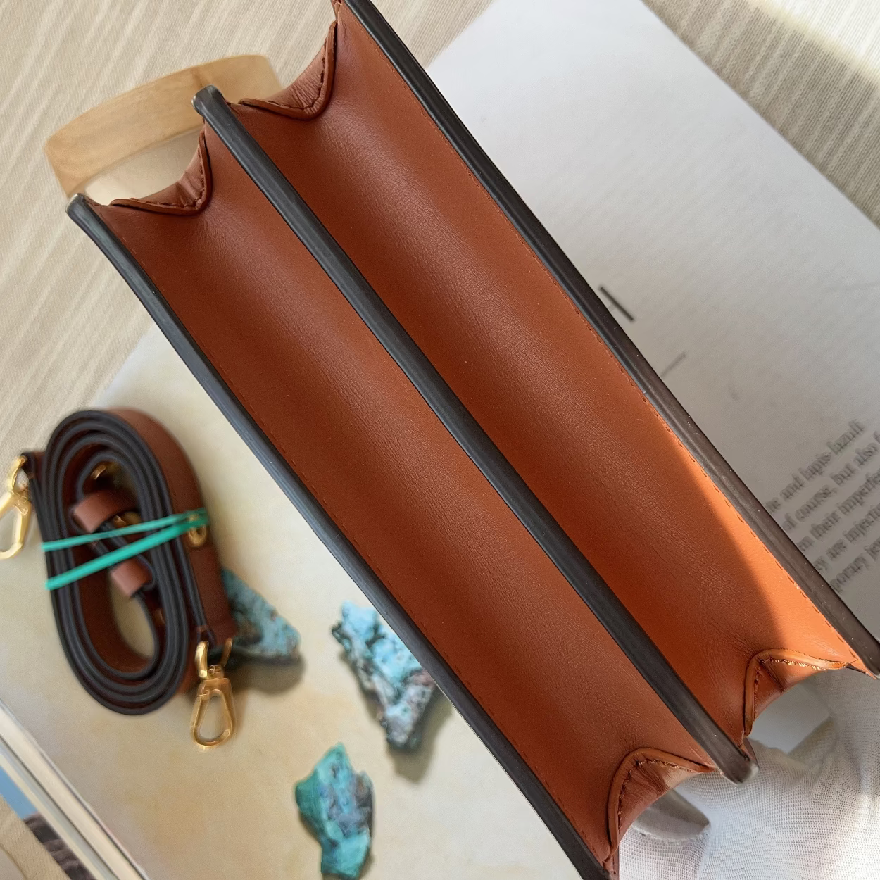 Brown leather pouch on an open book with a small keychain and turquoise stones.