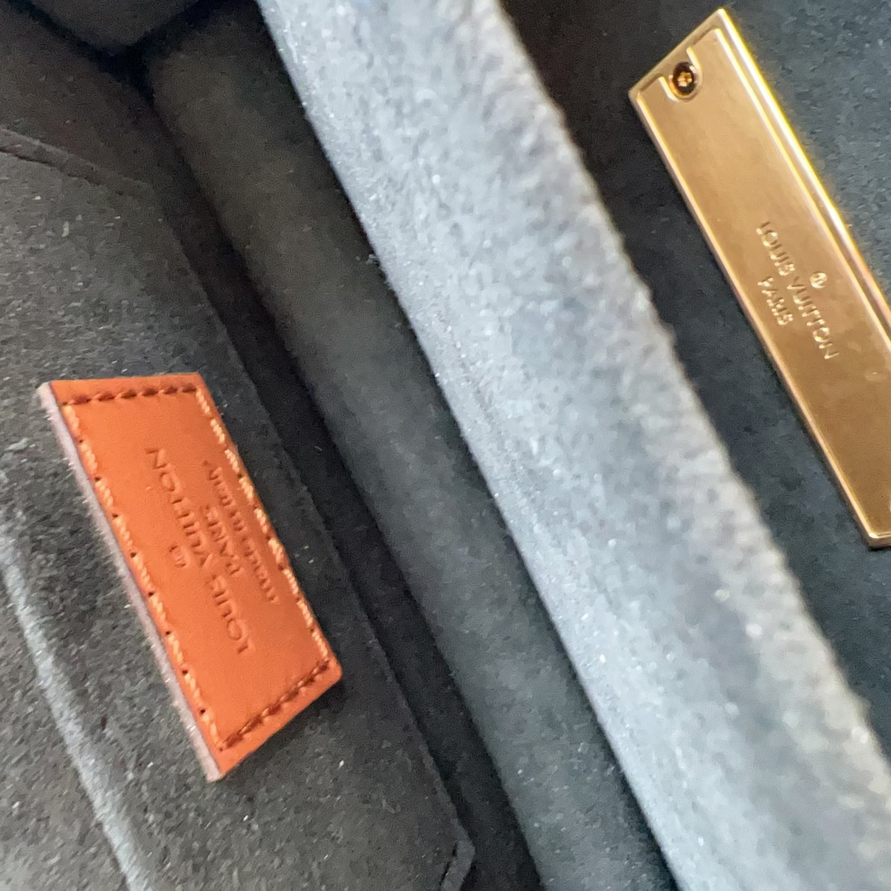 Close-up of a textured surface with a brown leather label and gold metal tag.