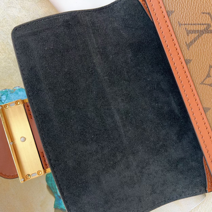 Close-up of a black suede clutch with gold clasp on a patterned surface