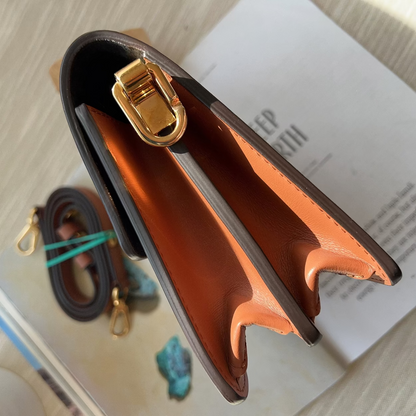 Brown leather wallet with gold buckle on a magazine