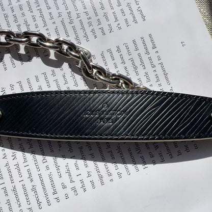 Black textured belt with silver chain on a piece of paper