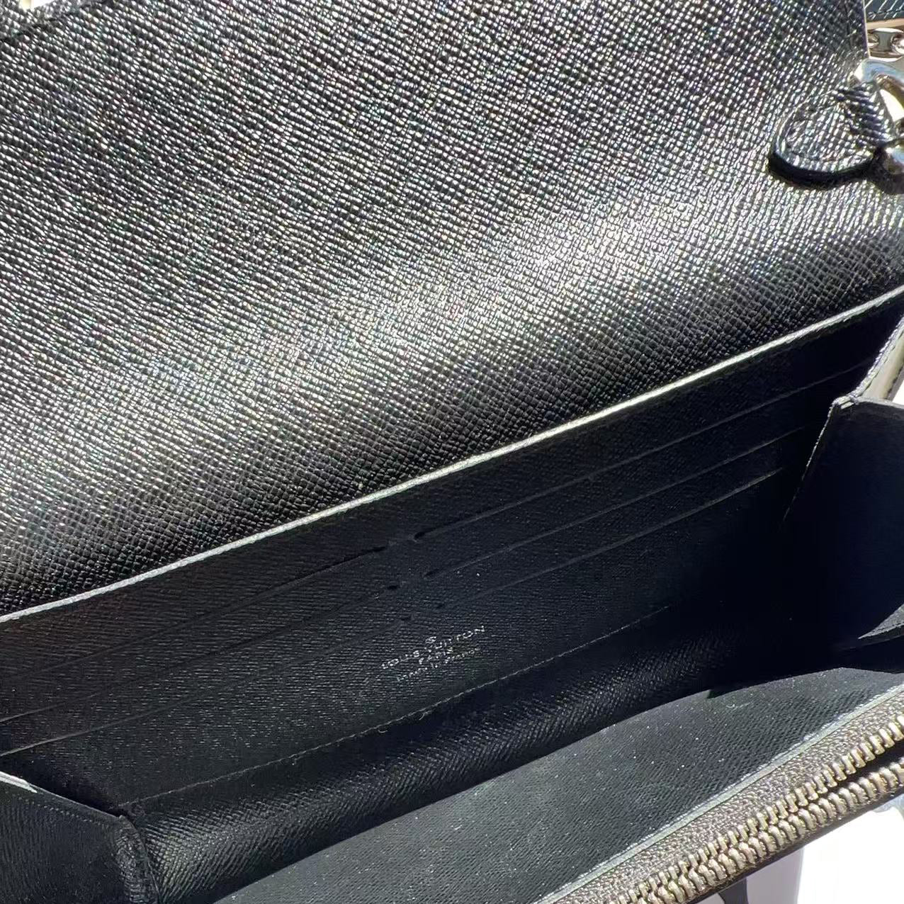 Black handbag with visible brand name on a reflective surface