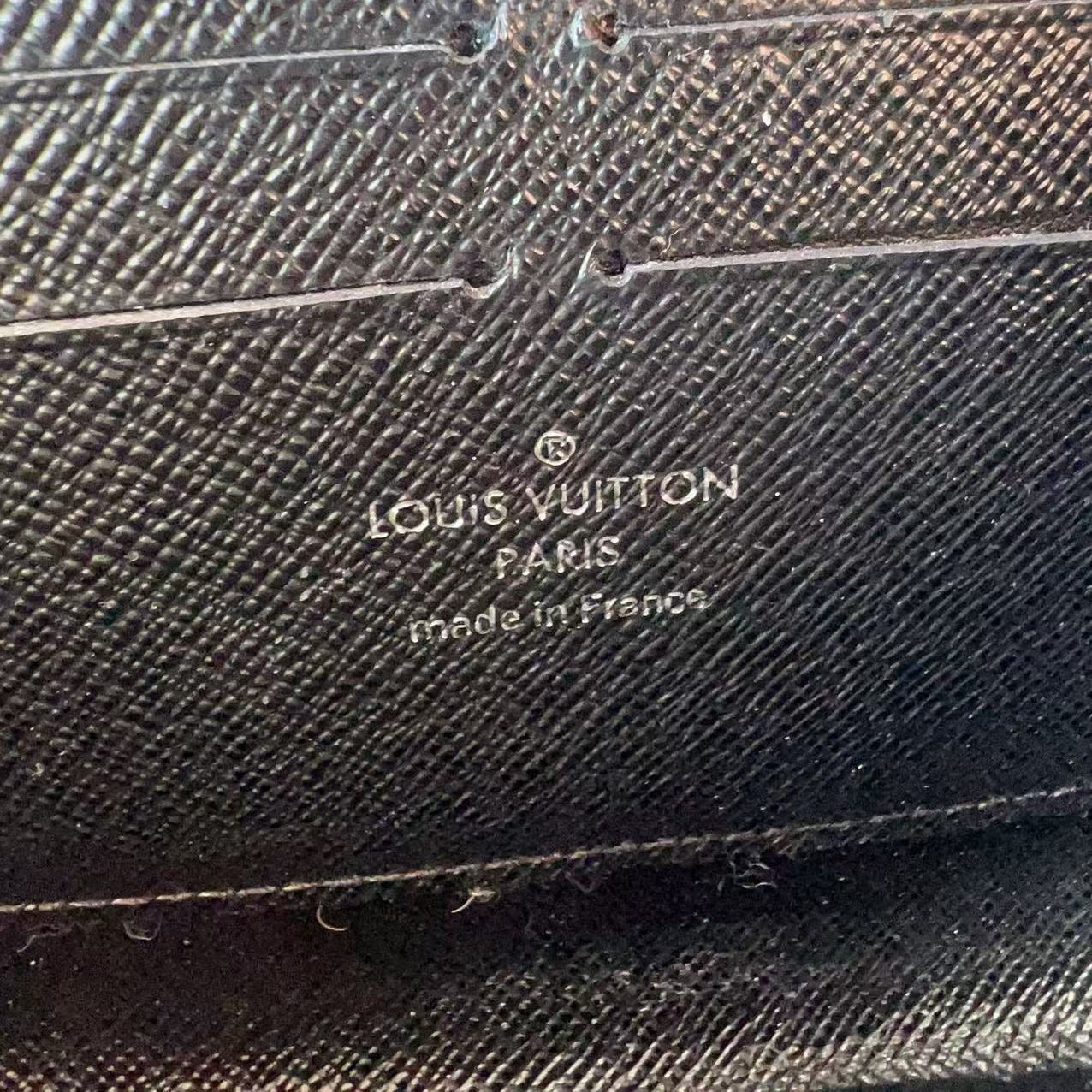 Louis Vuitton wallet with brand logo and 'made in France' text on textured leather surface