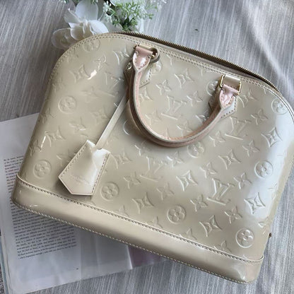 Beige handbag with brand logo on a textured surface