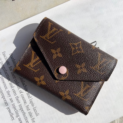 Brown wallet with monogram pattern on a textured surface