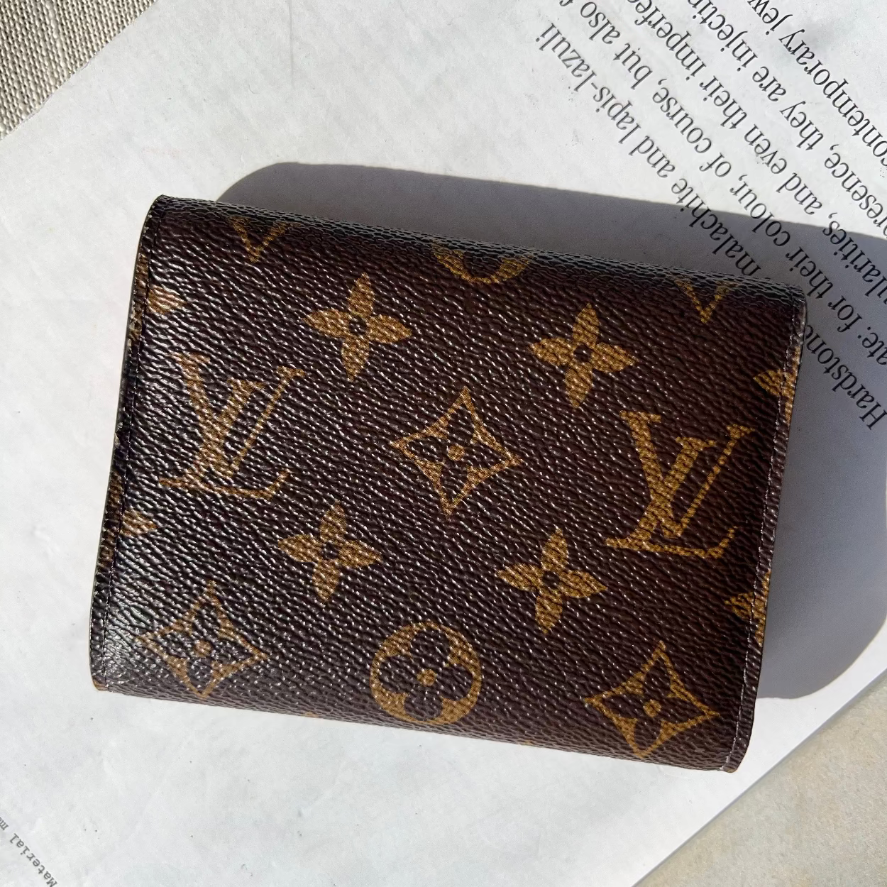 Louis Vuitton wallet with monogram pattern on a textured surface