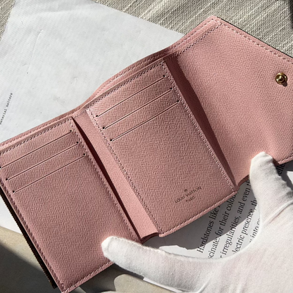 Pink wallet held by a gloved hand on a textured surface