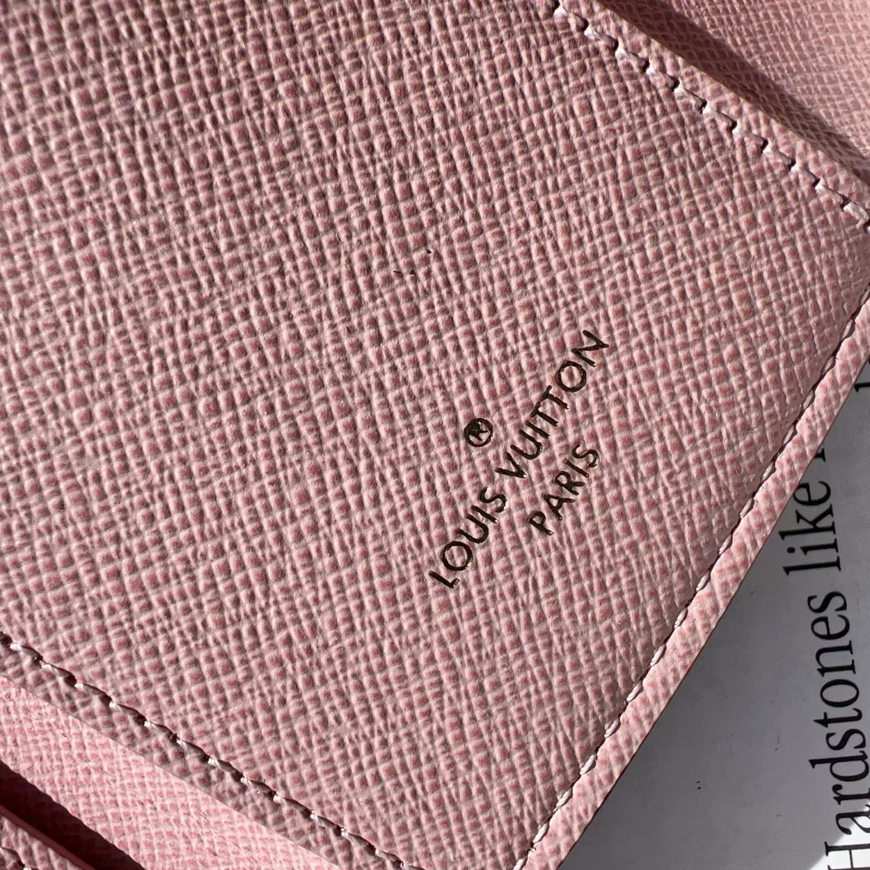 Close-up of a pink Louis Vuitton wallet with the brand logo.