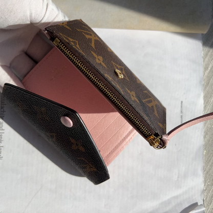 Louis Vuitton wallet and pink cardholder on a textured surface