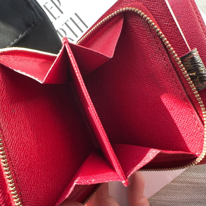 Red wallet with gold zipper on a textured surface