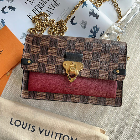 Louis Vuitton handbag with a red interior on a textured surface 