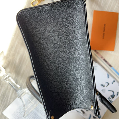 Black leather pouch on a textured surface with a visible brand name.
