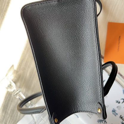 Black leather clutch bag on a white surface with a blurred background