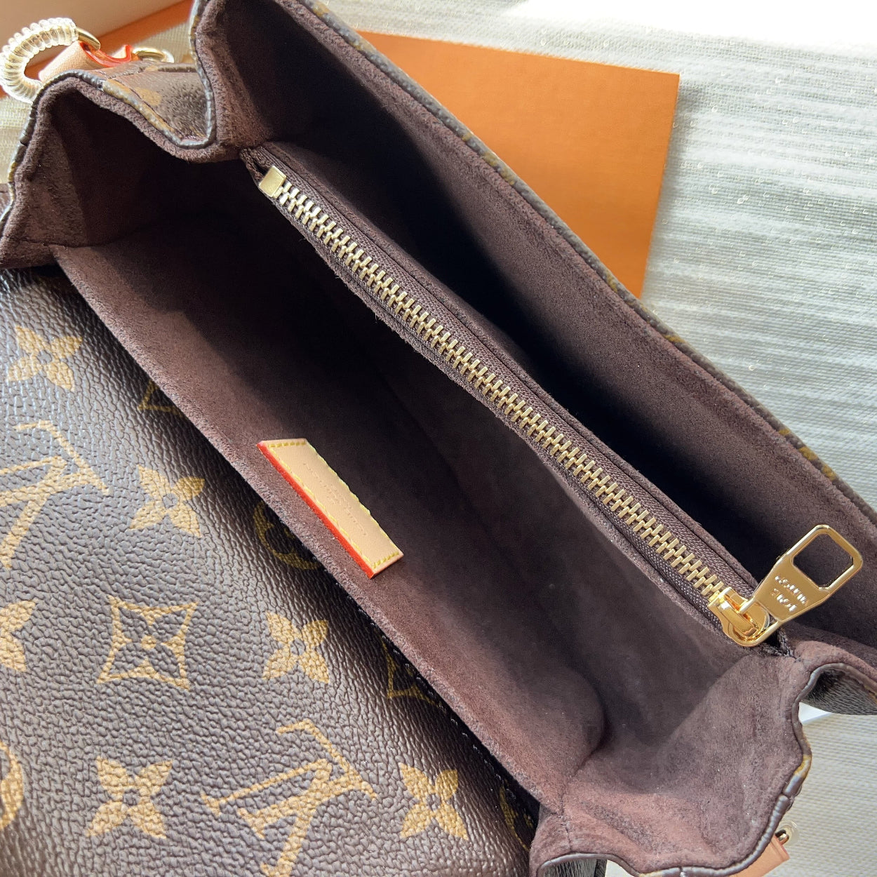 Brown handbag with gold zipper on a textured surface