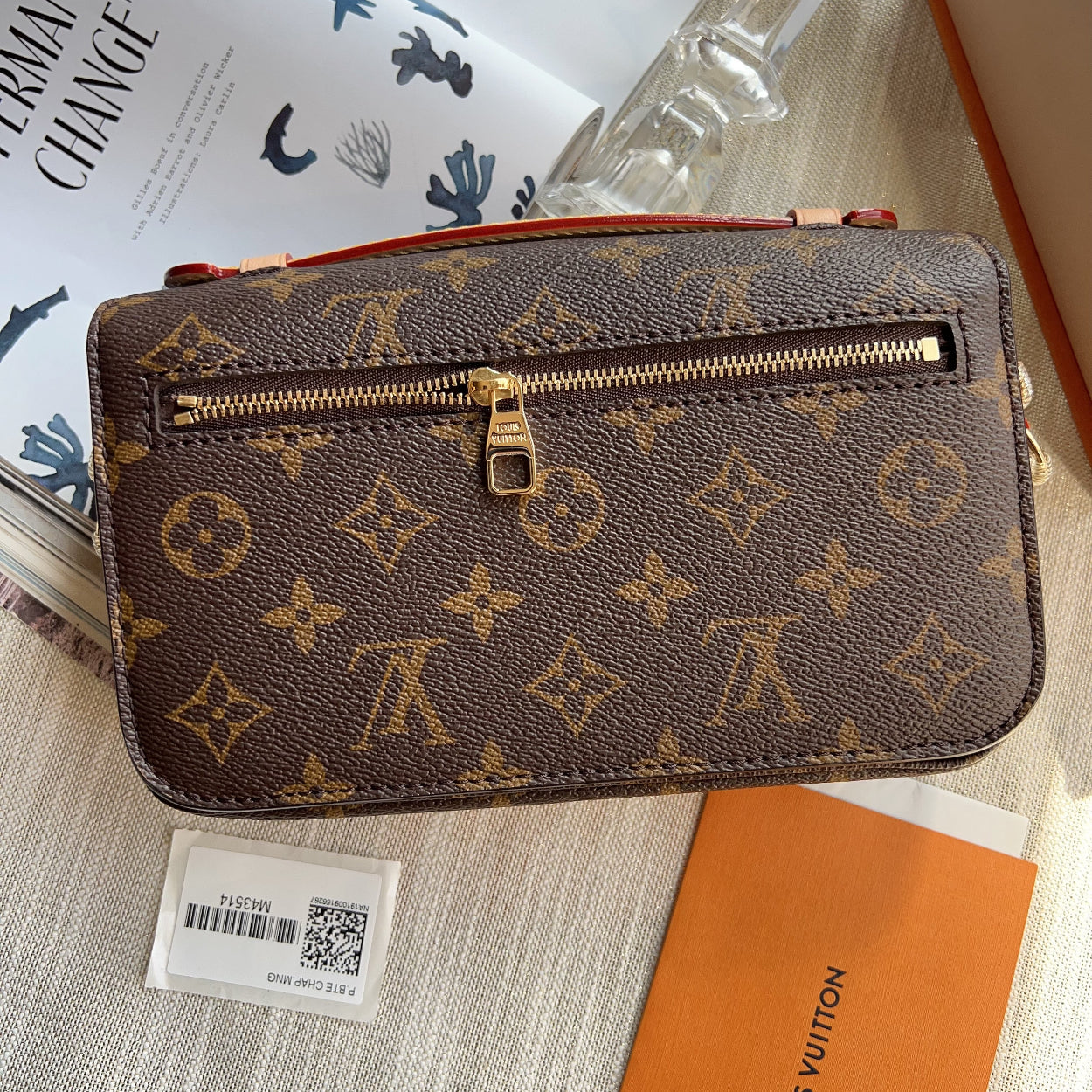 Louis Vuitton wallet with monogram pattern on a surface with a magazine and box.