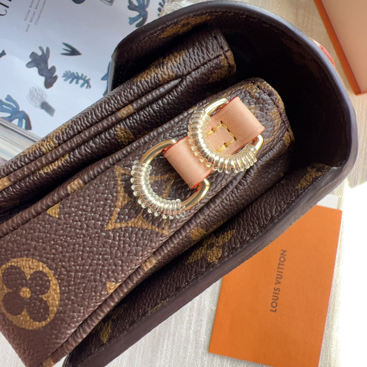 Louis Vuitton wallet with pink strap on a white surface