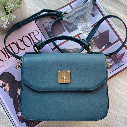 Teal handbag with gold clasp on a magazine
