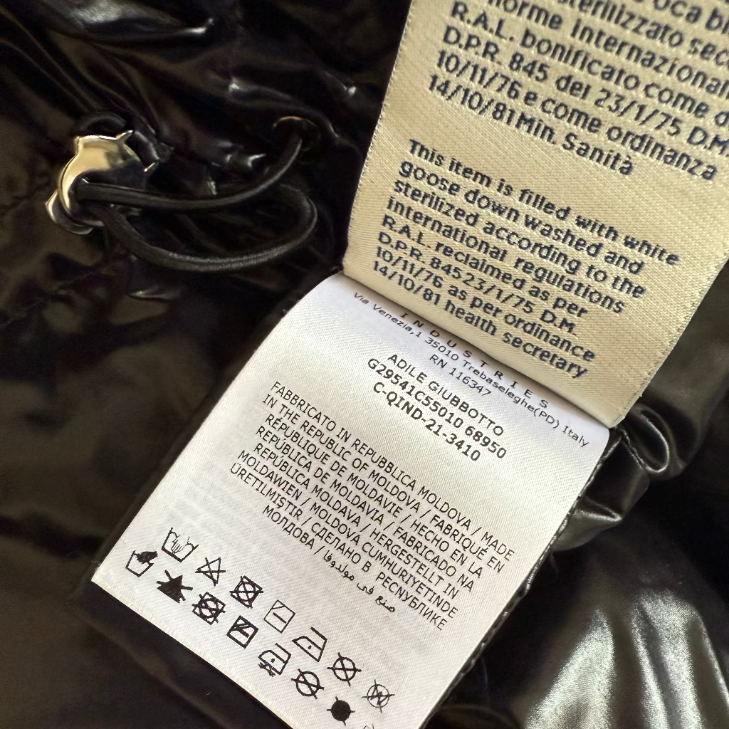 Close-up of a label on a black garment with text and symbols.