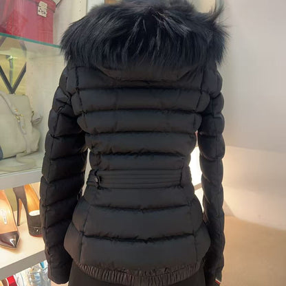 A black puffer jacket with a large black faux-fur trimmed hood, shown from the back on a mannequin inside a retail store.