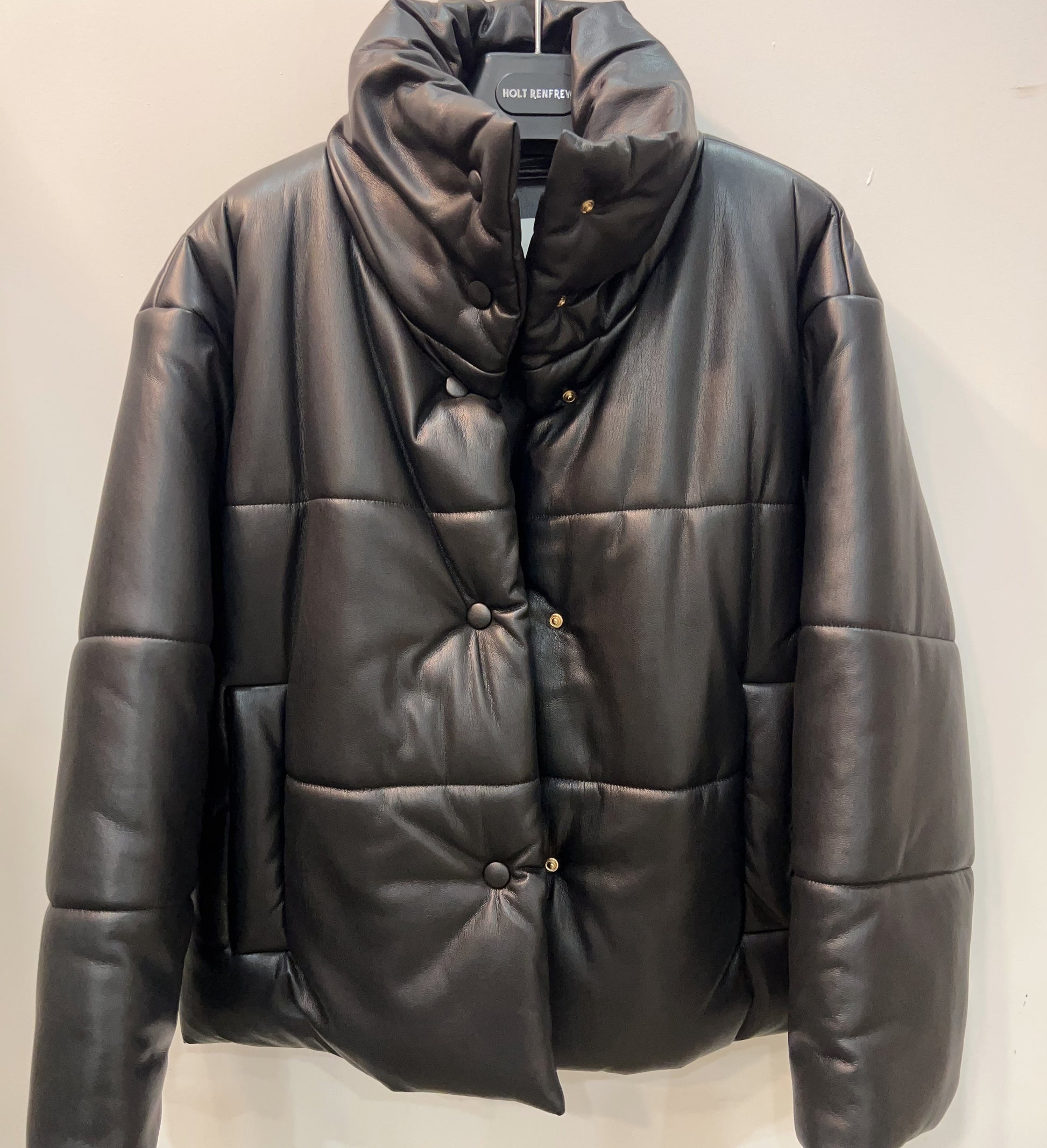 Black puffer jacket on a hanger against a white background