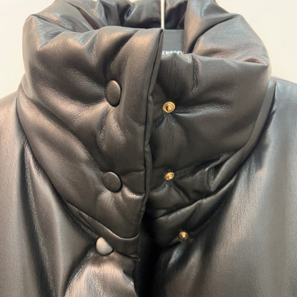 Close-up of a black leather jacket with button details on a plain background