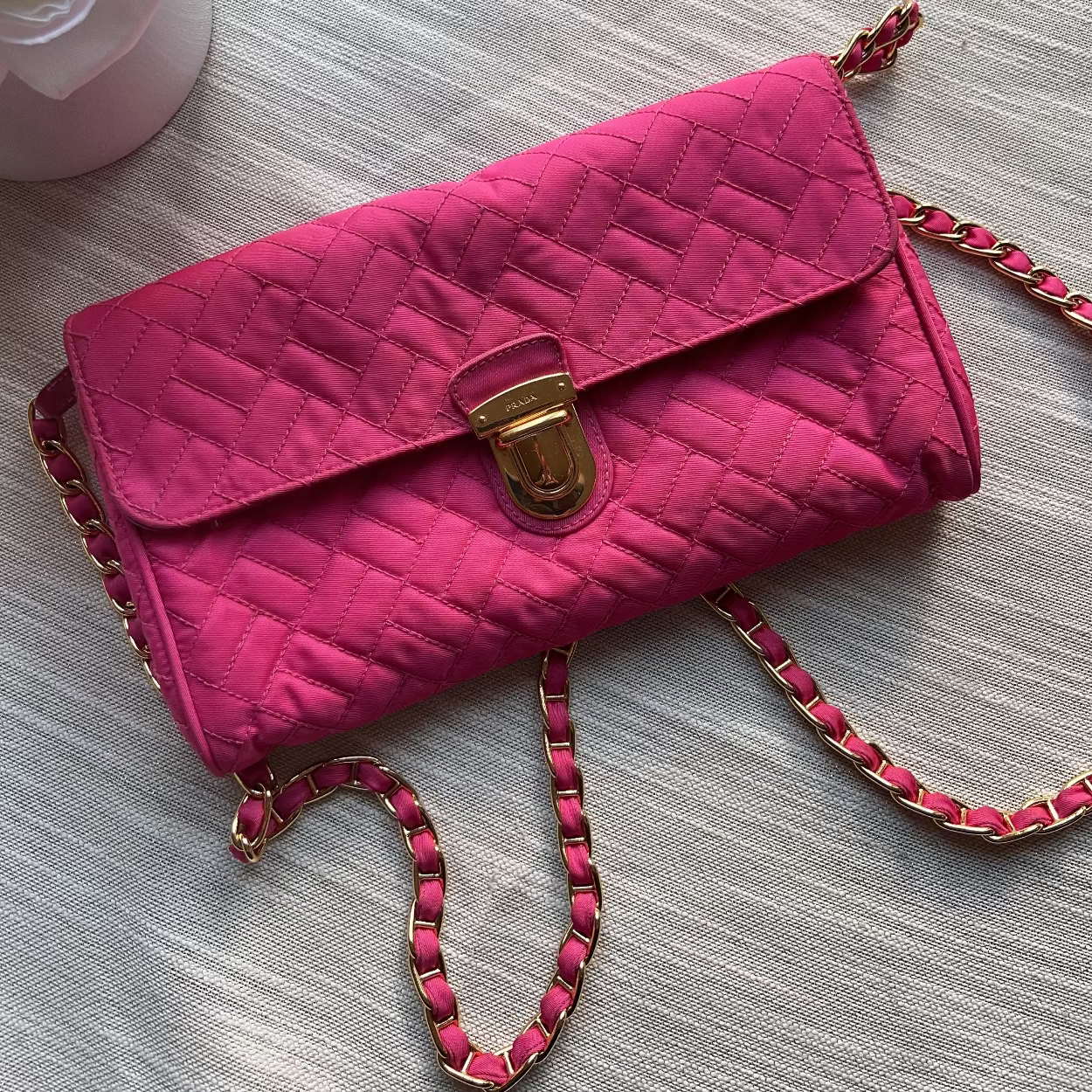 Pink quilted handbag with a gold clasp on a light gray surface